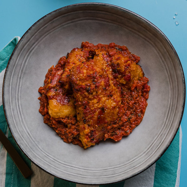Plated dish of food with a red sauce on a blue background